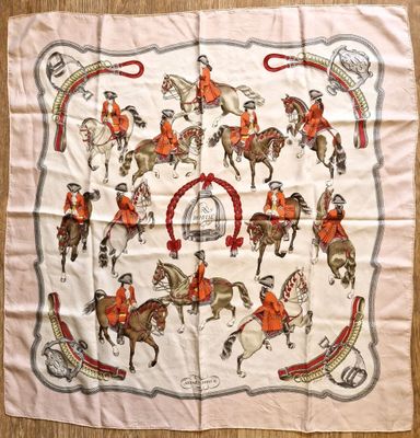 a white scarf with a picture of people riding horses on it