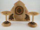 two candles and a clock sitting on a table