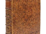 un vieux livre à la couverture brune posé sur une surface blanche