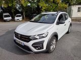 La voiture blanche est garée sur le parking, près des arbres.