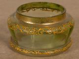 a green glass jar with a gold decoration on it