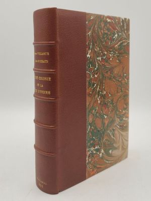 un vieux livre à la couverture marron posé sur une table blanche