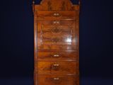 an antique chest of drawers with a carved top on a dark background