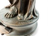a bronze statue of a woman sitting on top of a table
