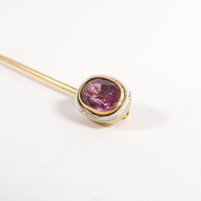 a close up of a gold stick with a pink stone on it