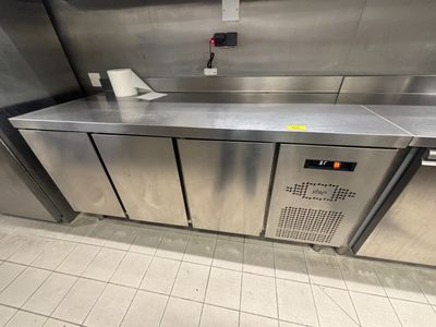 un plan de travail en acier inoxydable dans une cuisine professionnelle, équipé d'un distributeur de papier