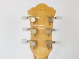 a close up of a guitar head on a stand