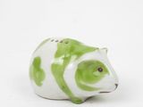 une figurine d'animal verte et blanche posée sur une surface blanche