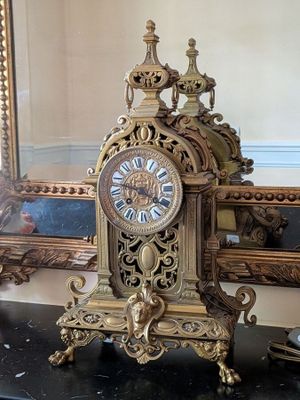 a gold clock sitting on a table in front of a mirror