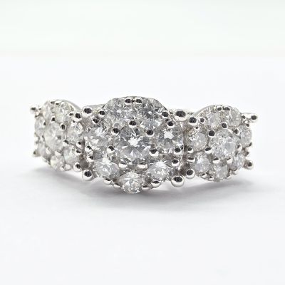 a close up of a three stone diamond ring on a white background