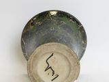 a green and black vase sitting on a white surface