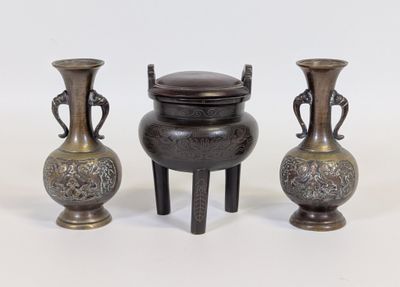 trois vases en métal munis d'anses, placés les uns à côté des autres