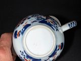 a hand holding a cup with a blue and white design