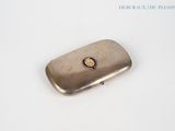 a silver cigarette case with a gold emblem on it