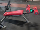 a red and black bench in a gym with other equipment