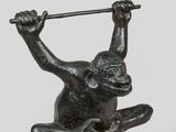 bronze statue of a monkey holding a bar on a base