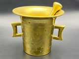 a gold vase with a spoon in it on a table