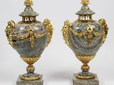 une paire de vases en argent et en or posés sur des socles, sur fond blanc