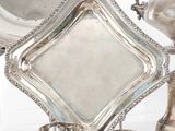 un plateau en argent avec des tasses et des soucoupes en argent posées sur une table