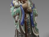 une vieille figurine représentant un homme barbu muni d'une canne