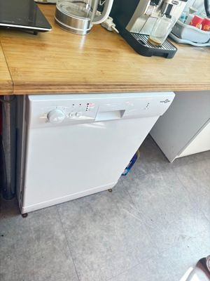 un lave-vaisselle blanc posé sur un plan de travail en bois