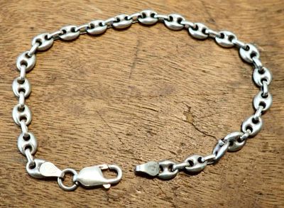a close up of a silver chain bracelet on a wooden surface