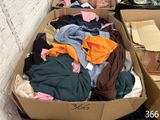 une boîte en carton remplie de vêtements posée par terre