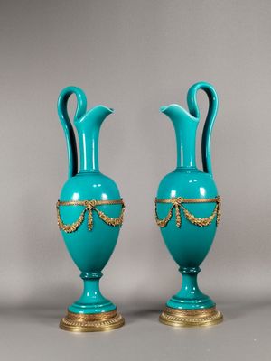 une paire de vases bleus avec des bordures et des anses dorées sur fond gris