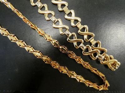 three different types of gold chains on a black surface