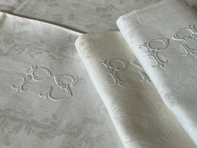 three napkins with embroidered designs on them on a table