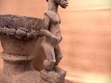 a statue of a woman holding a bowl in front of a wall