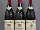 trois bouteilles de vin rouge sont posées sur une table en verre