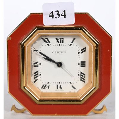 une petite horloge rouge avec des chiffres romains