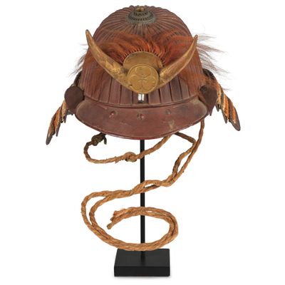 un vieux casque orné de cornes et de plumes est posé sur un socle