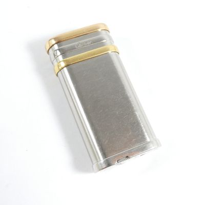 un briquet argenté et doré posé sur une surface blanche