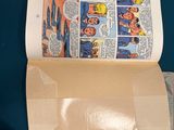 a person holding a piece of paper with a comic book inside of it