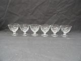 six glass goblets lined up in a row on a black background
