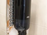 un distributeur de savon noir fixé au mur d'une salle de bains
