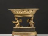 un plateau en or orné de deux anges et surmonté d'un bol
