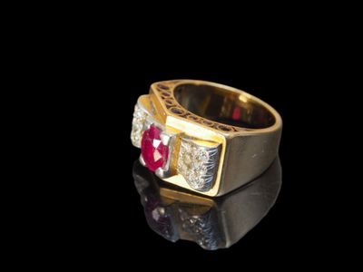 gros plan d'une bague en or avec une pierre rouge