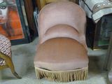 une chaise rose ornée de franges, placée devant des tableaux