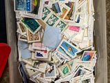 un récipient en plastique rempli de timbres-poste, posé par terre