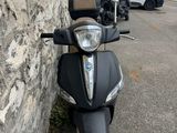 un scooter garé près d'un mur de pierre, avec une camionnette en arrière-plan