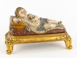 une statue représentant un homme allongé sur un lit sur lequel se trouve un bébé