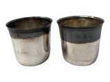 two silver cups with black rims are sitting side by side