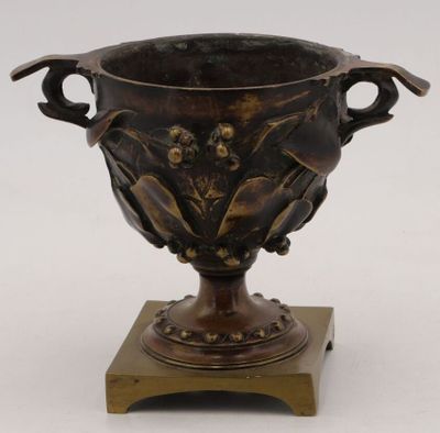 a bronze vase on a wooden stand on a white background
