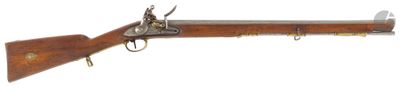 un vieux fusil avec un canon en bois et des accessoires en laiton sur fond blanc