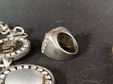 a silver ring with a picture on it next to a coin