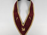 a close up of a red and gold collar on a white background