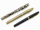 trois types de stylos différents sont alignés sur une surface blanche